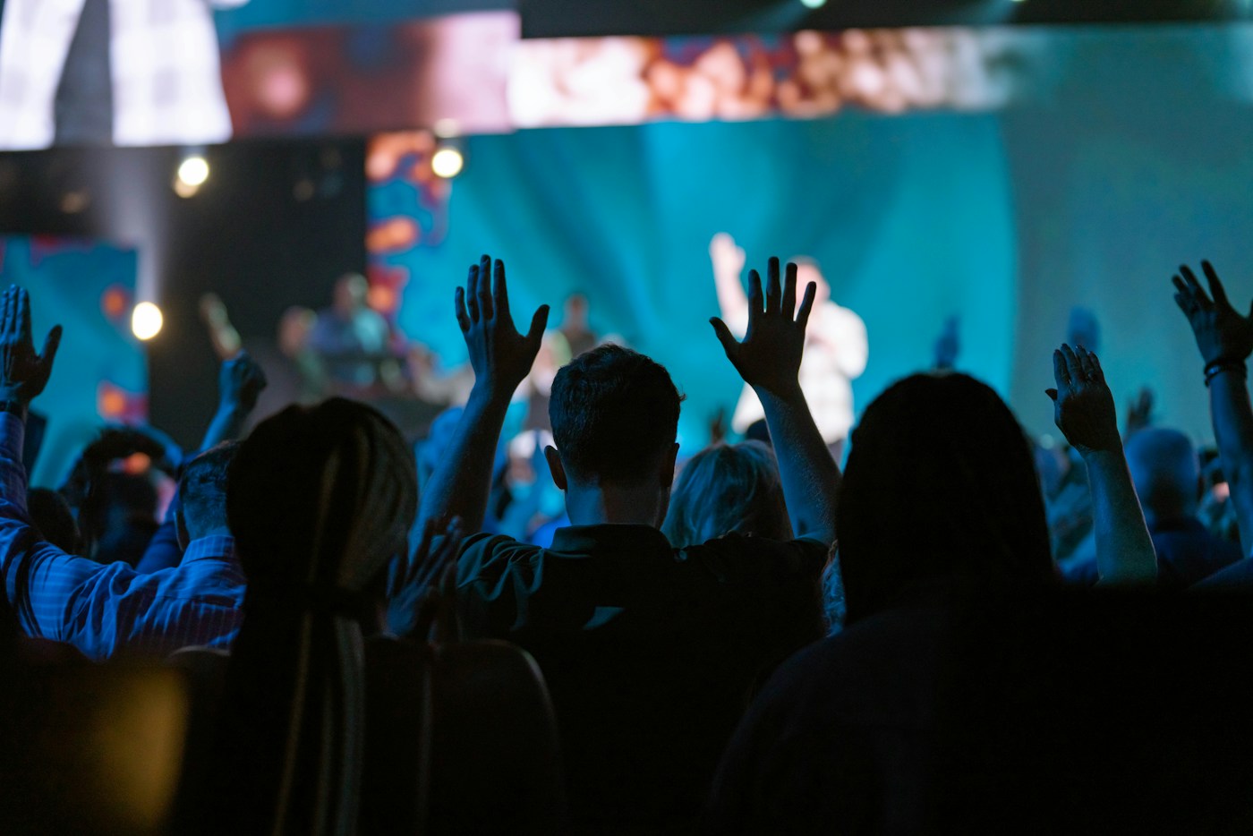 A congregation gathered in worship beneath blue stage lighting